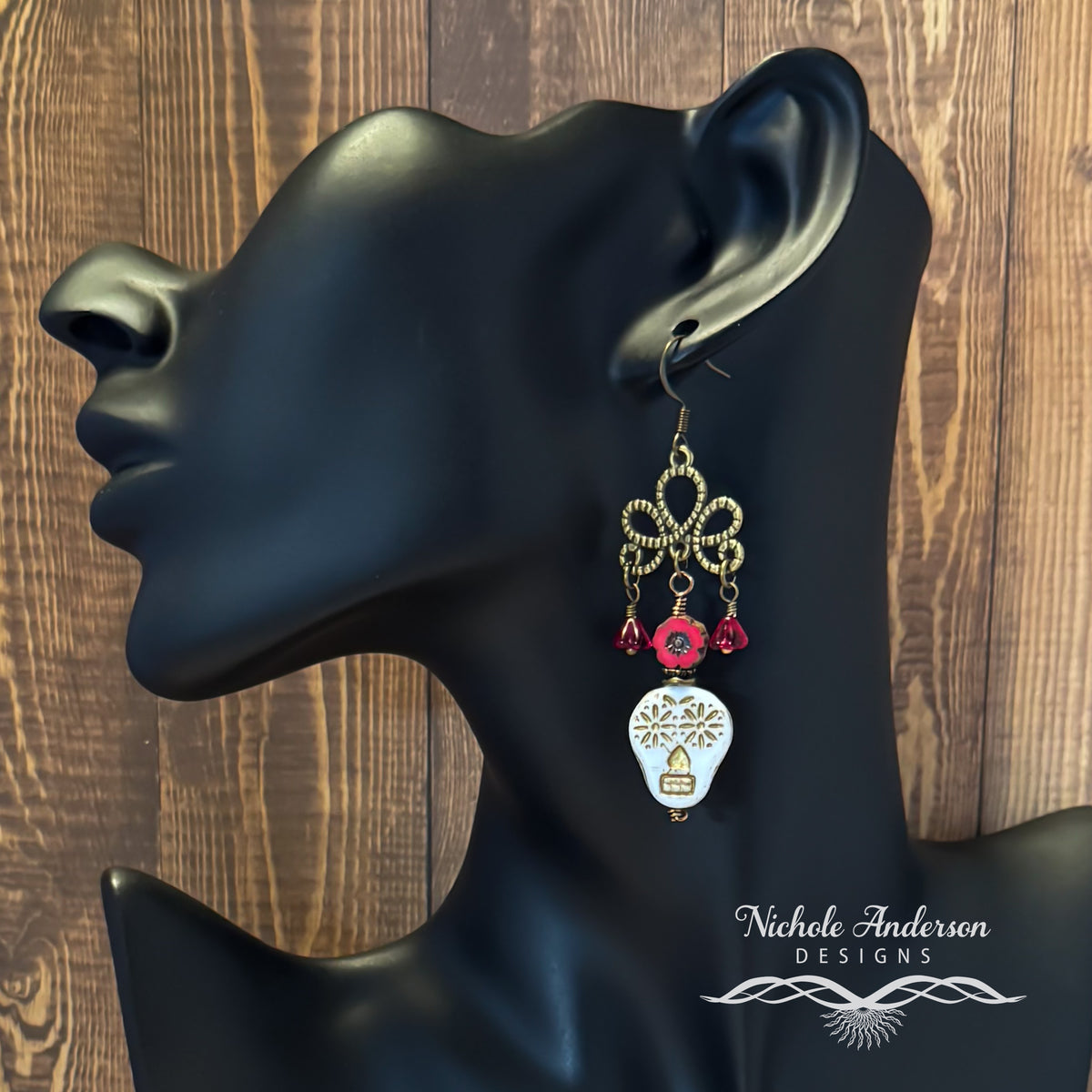 Sugar Skull Chandelier Flower Earring displayed on a black mannequin ear with a wooden background, featuring the brand 'Nichole Anderson Designs'.